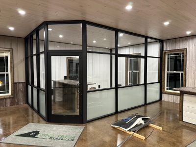 Modern glass office with black framing inside a wooden room.