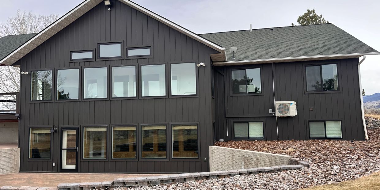Modern dark-paneled house with large windows.