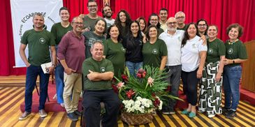 Group of smiling people posing indoors with a flower arrangement.