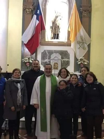 Group photo inside a church with a priest and parishioners.