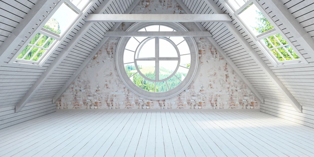 Bright attic room with white wooden walls and large circular window.