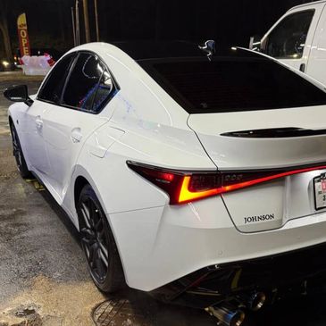 White Lexus sedan rear bumper and tail lights detailed with ceramic coating and trim restoration.