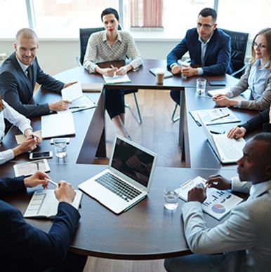 Business team engaged in a meeting around a conference table with laptops and documents.