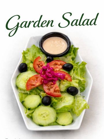 Fresh garden salad with lettuce, cucumbers, tomatoes, black olives, and dressing.