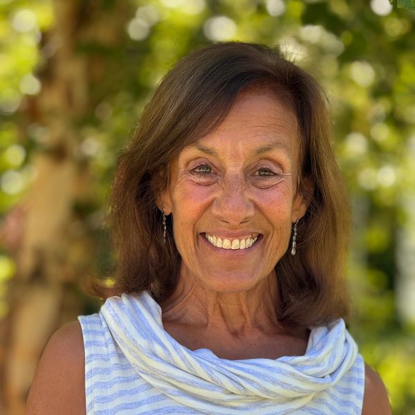 Smiling woman outdoors with blurred green background.