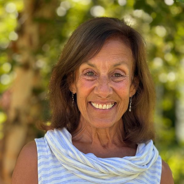 Smiling woman outdoors with blurred green background.