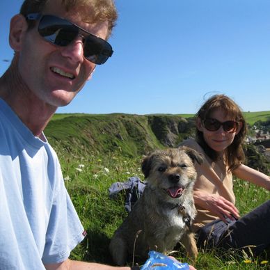 Couple with their dog sitting outdoors on a sunny day.