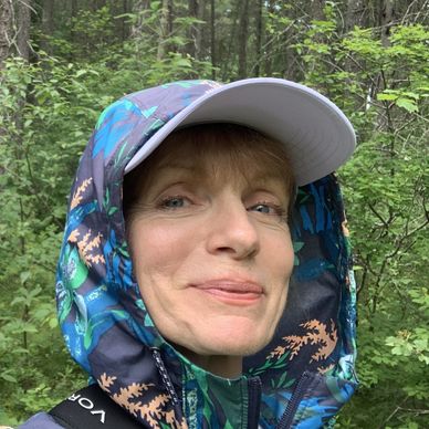 Woman in a colorful jacket and cap outdoors.