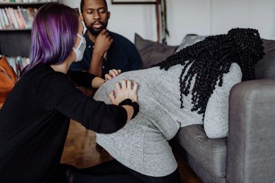 A doula squeezes the hips of a pregnant client as the partner observed 
