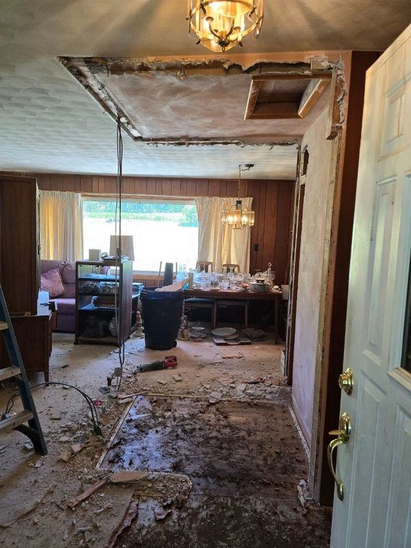 A room under renovation with exposed ceiling and debris on the floor.