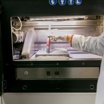 Scientist brushing powder on a sample inside a lab machine.