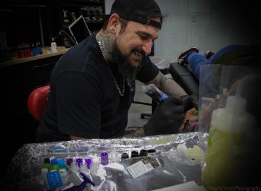 Tattoo artist working on a client in a studio.