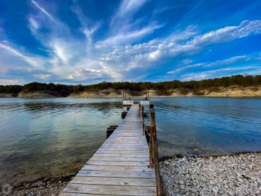 Wooden dock extending over calm lake under a vibrant sky.