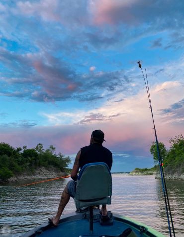 Person fishing on a lake during sunset.