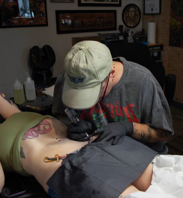 Tattoo artist working on a person's ribs.