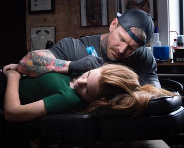 Tattoo artist working on a woman's arm.