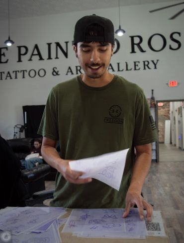 Man looking at tattoo design sketches in an art gallery.