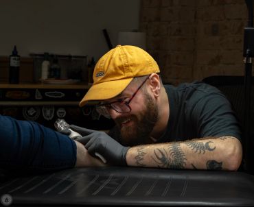Tattoo artist working on a client's arm.