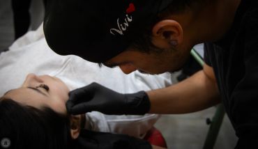 Tattoo artist working on a client's face.