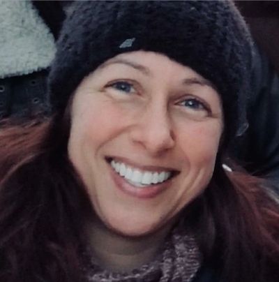 Smiling woman wearing a black beanie outdoors.