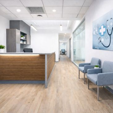 Modern medical clinic reception area with wooden desk and blue chairs.