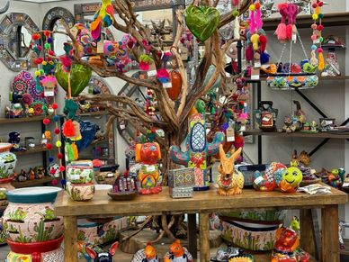 Colorful handmade crafts and decorations displayed on a wooden table and tree.