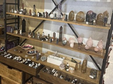 Wooden shelves displaying various crystals and mineral specimens in a store.