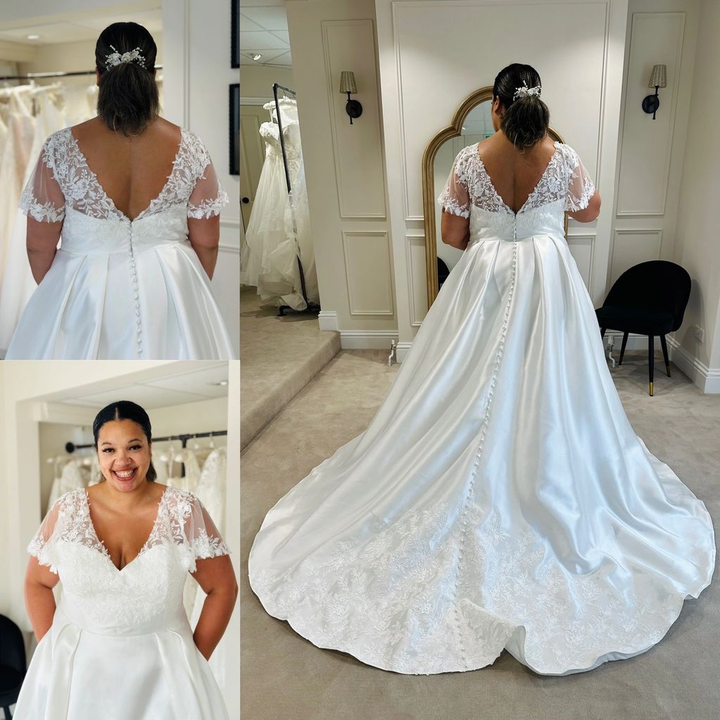 Woman happily wearing a white lace wedding dress with floral details.