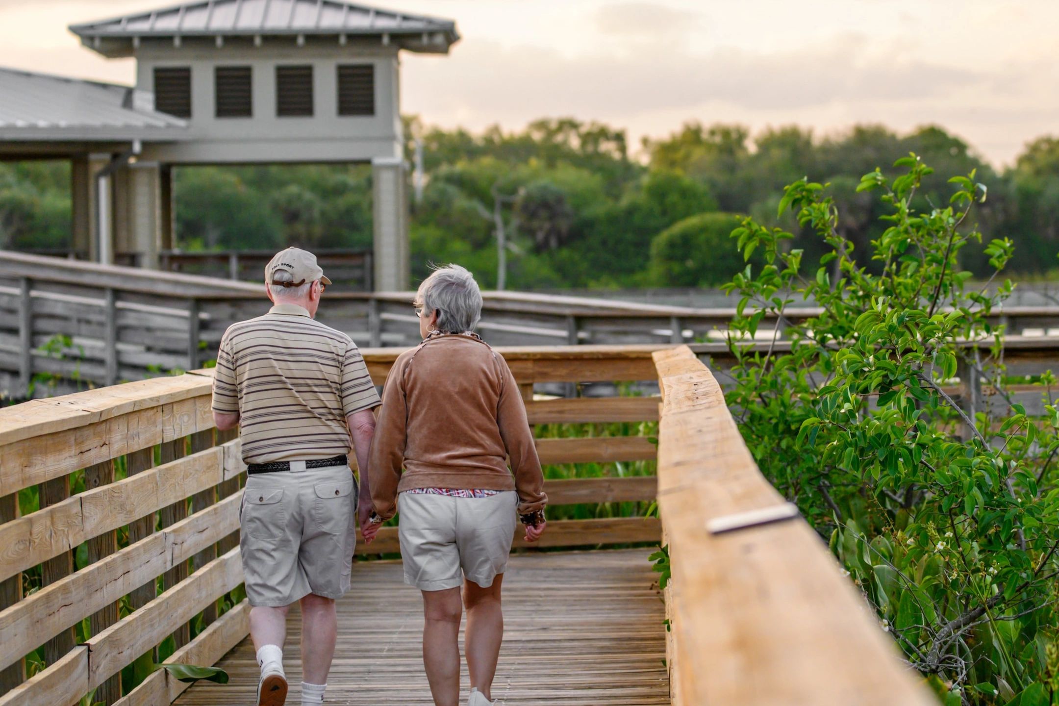 Senior couple walking hand in hand on a boardwalk
