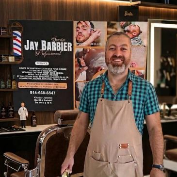 Barbier souriant dans son salon de coiffure.