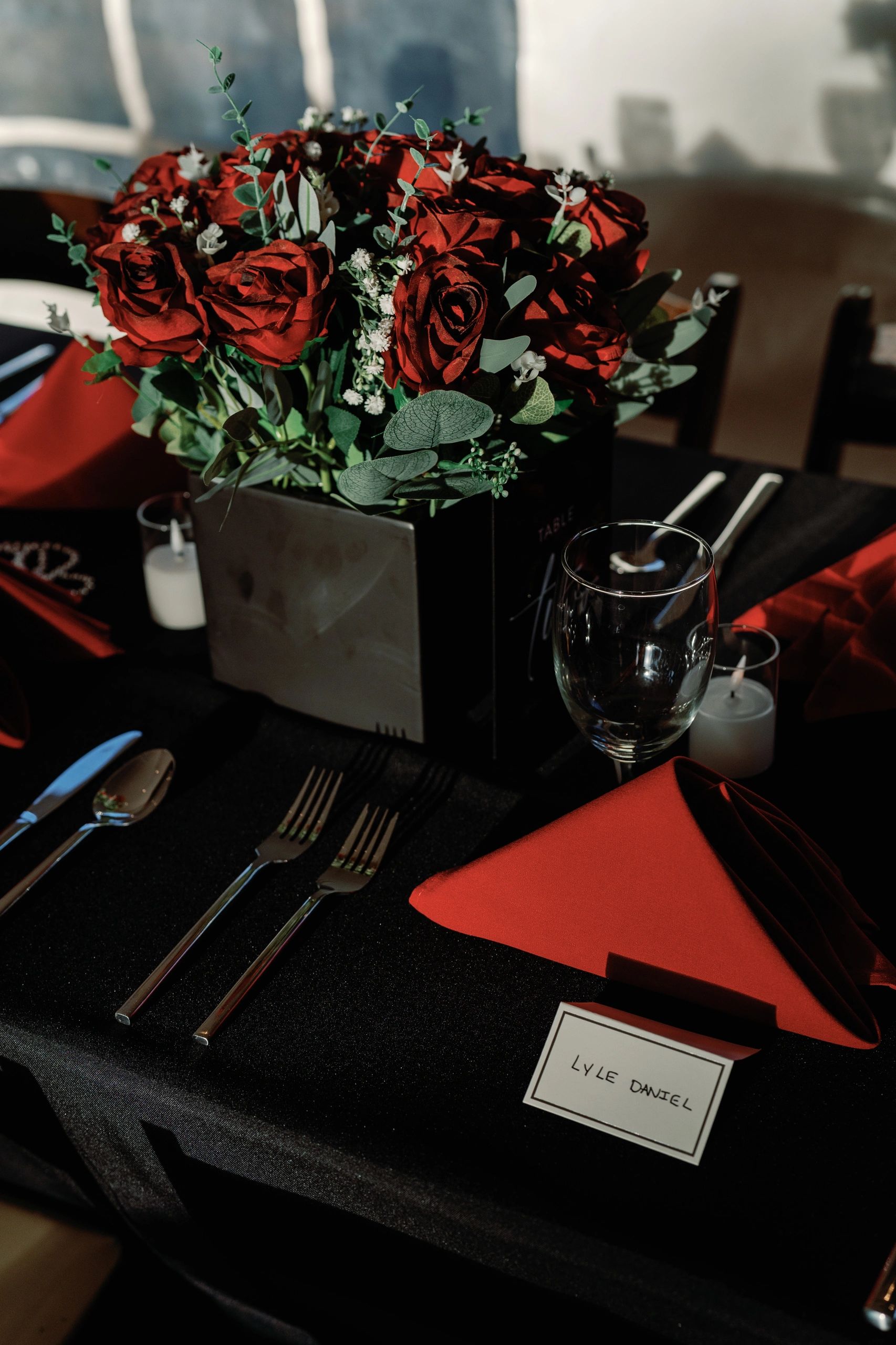 Elegant dining table with red roses and personalized place card.