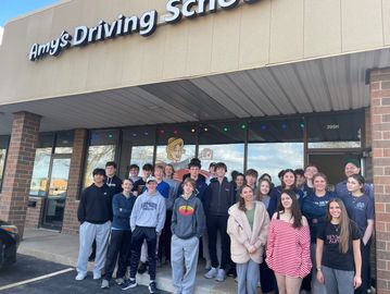 Group of young people standing outside Amy's Driving School.