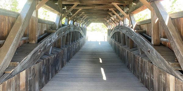 View inside a wooden covered bridge with curved beams.