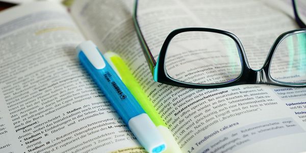 book with glasses and highlighters. Photo by pixabay