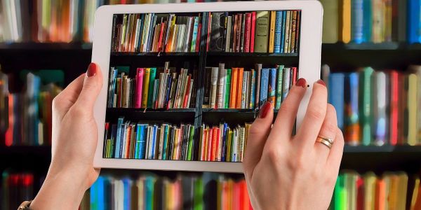 looking at bookshelves through an iPad screen. Photo by pixabay