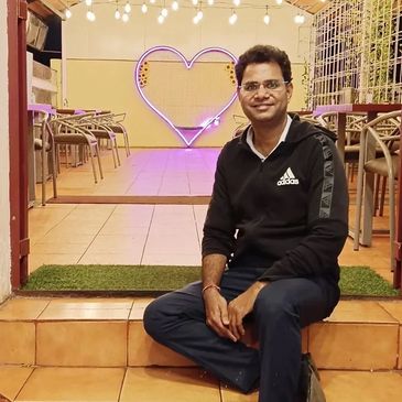 A man sitting on steps with a glowing heart decoration behind him.