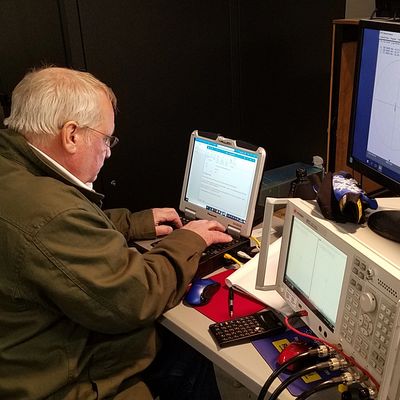 Older man working on a laptop in a technical setup.