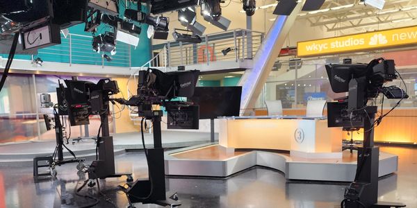 Inside a modern TV news studio with cameras and lighting.