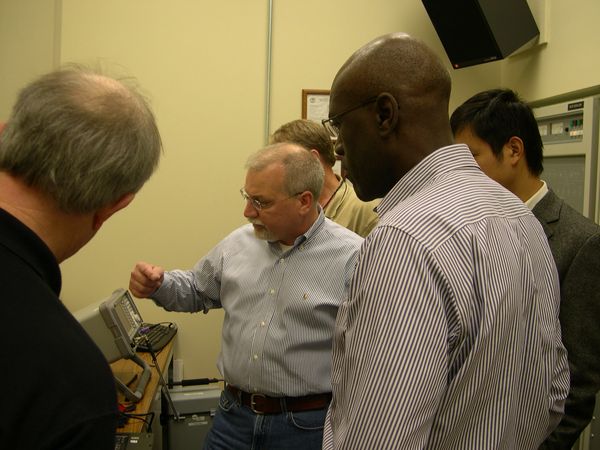 Group of men examining electronic equipment.