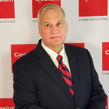 Man in suit and striped tie posing in front of a red and white backdrop.