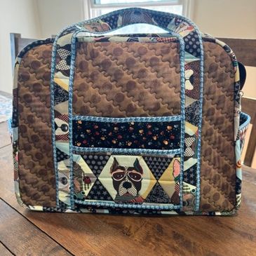Quilted bag with dog pattern and blue trim.