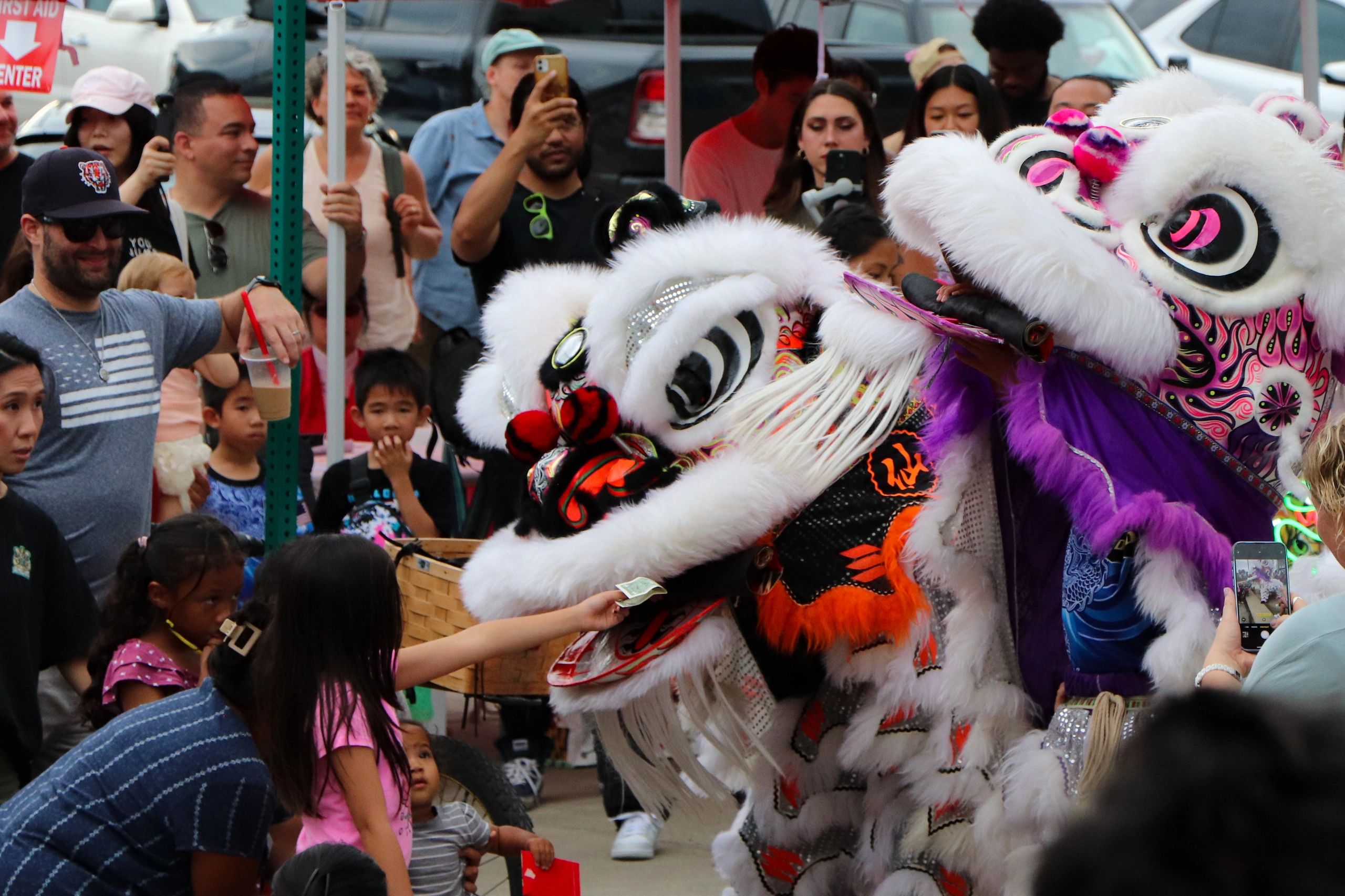 A girl offers money to a lion dance performer during a festive event.
