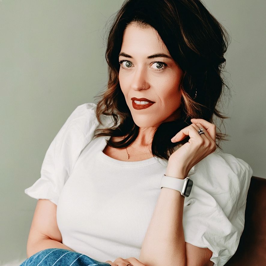 Woman with a white top and smartwatch posing confidently.