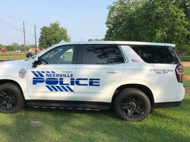 Needville Police SUV parked on grass.