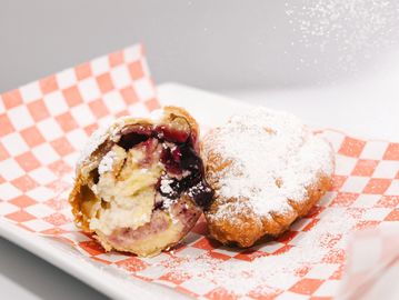 Two powdered sugar-dusted pastries on checkered paper.