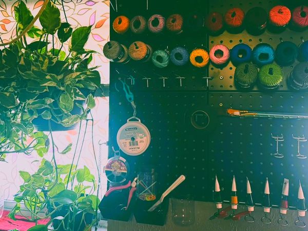 Organized craft supplies and hanging plants by a sunlit window.