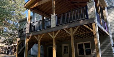 Wooden elevated deck with black railing on a house.