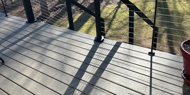 Sunny backyard deck with shadows and railing.