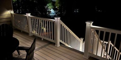 Well-lit deck railing and stairs at night.