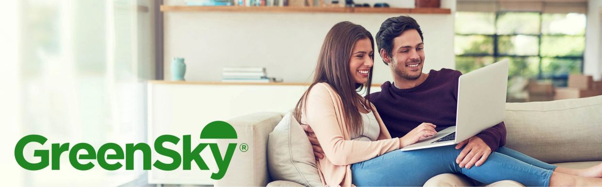 Couple smiling using laptop with GreenSky logo.